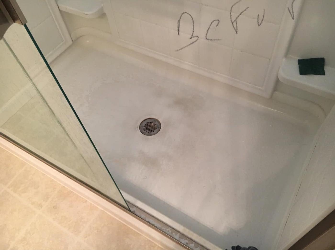 Shower floor behind a glass door, before we cleaned it
