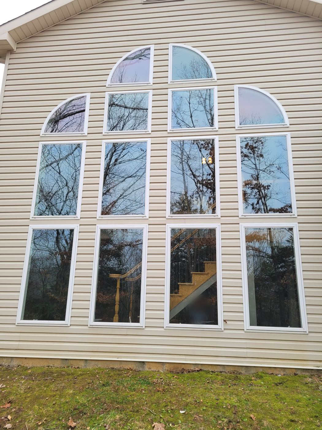 A two-story wall of tall and arched windows on beige siding